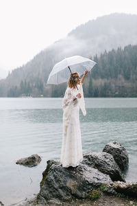 Woman standing by lake with mountain in background