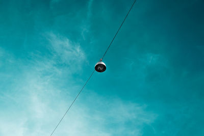 Low angle view of lighting equipment hanging against blue sky