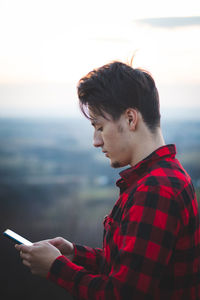 Portrait of a twenty-three year old man in a black and red checked shirt, communicating 