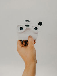 Close-up of hand holding toy against white background