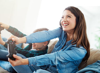 Smiling young woman playing video game at home