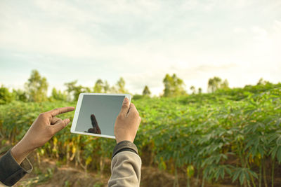 Man holding mobile phone against sky