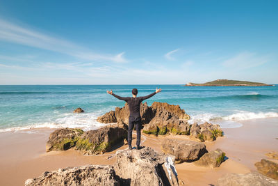 Rear view of woman standing at beach against sky