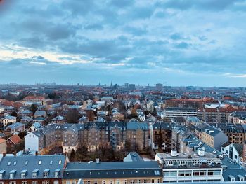 High angle view of city buildings against cloudy sky