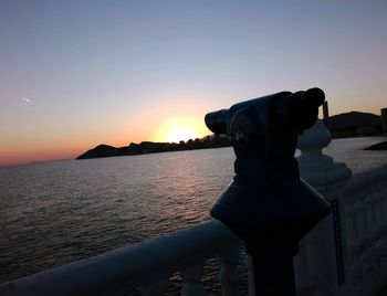 Close-up of man photographing against sky during sunset