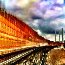 Railroad tracks against cloudy sky