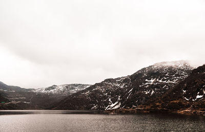 Scenic view of lake by mountains against sky