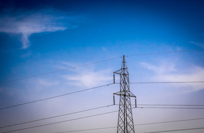 Low angle view of electricity pylon against blue sky