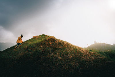 Man climbing on mountain against sky