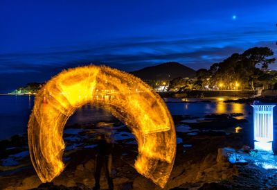 Illuminated light by water against sky at night