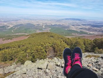 Low section of woman wearing shoes resting on mountain