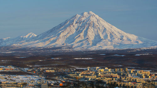 Aerial view of townscape by mountain against sky