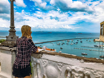 Rear view of woman standing by sea against sky