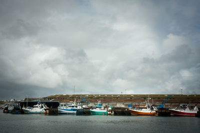 Boats moored at harbor against sky