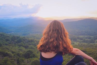 Woman looking at mountains against cloudy sky