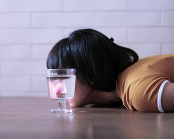 Side view of woman leaning on table with reflection