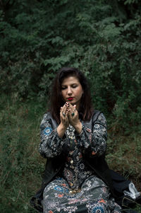 Young woman kneeling on grassy field in forest