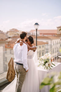 Rear view of couple holding hands against blue sky