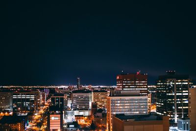 High angle view of illuminated buildings against clear sky at night