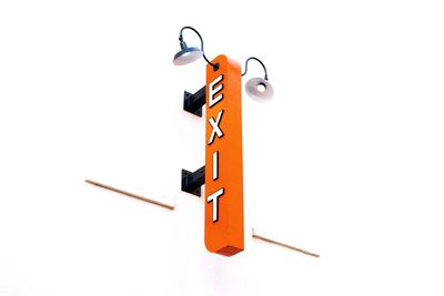 Low angle view of neon exit sign on white wall