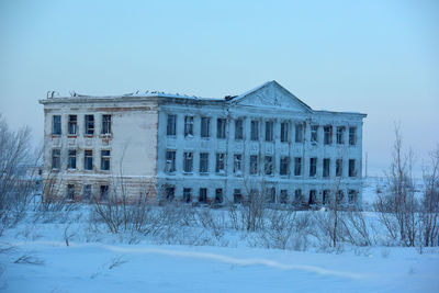 Building on snow covered field against sky