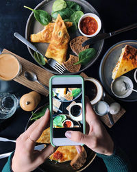 Cropped hands of woman photographing food with smart phone on table