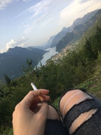 Low section of woman hand on mountain against sky