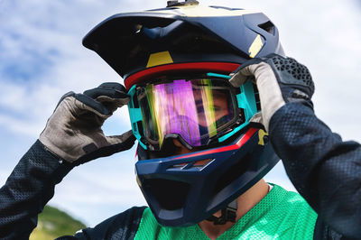 Professional well-equipped cyclist stands and adjusts his safety glasses, portrait. freeride and off