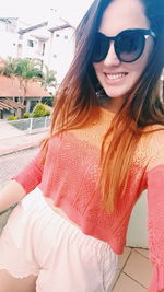 Close-up portrait of smiling young woman against sky