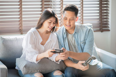 Young man using mobile phone while sitting on sofa