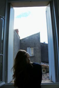 Rear view of woman sitting at window