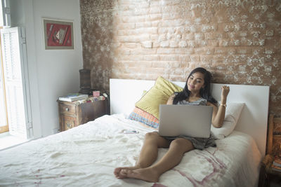 Young woman using her laptop computer on her bed