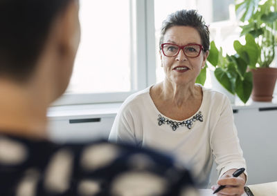 Mature businesswoman discussing with colleague about project in board room