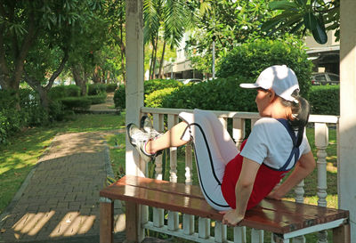 Full length of woman sitting on bench outdoors