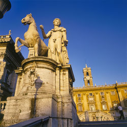 Low angle view of statue against building against clear blue sky