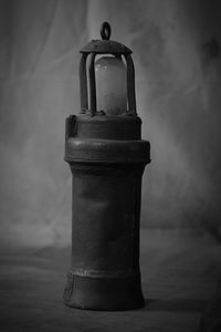 Close-up of old lamp on table against wall