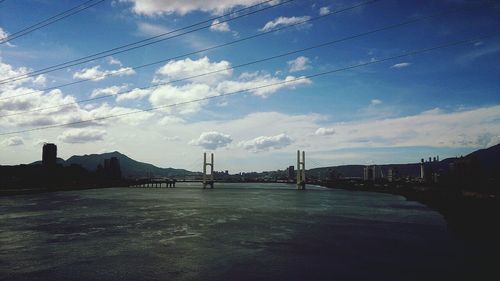 Bridge over river against cloudy sky