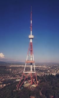 Communications tower on field by buildings against blue sky