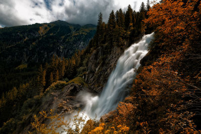 Scenic view of waterfall in forest against sky