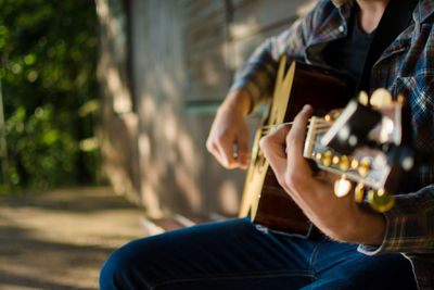 Midsection of man playing guitar