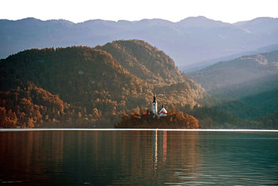 Scenic view of lake and hills against sky, natural light, sun beams.