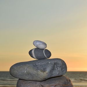 Close-up of stone stack on rock against sea during sunset