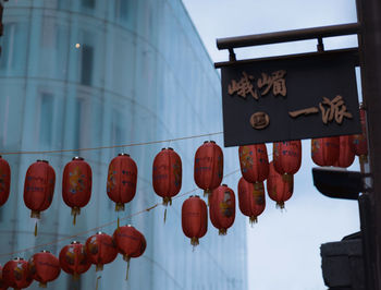 Low angle view of lanterns hanging by building against sky