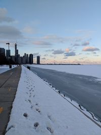 Scenic view of snow covered buildings against sky during sunset