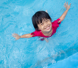 Directly above portrait of cheerful girl in swimming pool