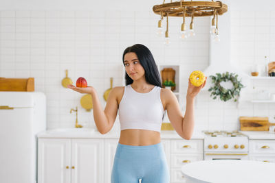 Young woman makes a choice between a peach fruit and a donut. the concept of diet and healthy eating