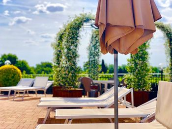 Empty chairs and tables at cafe against sky