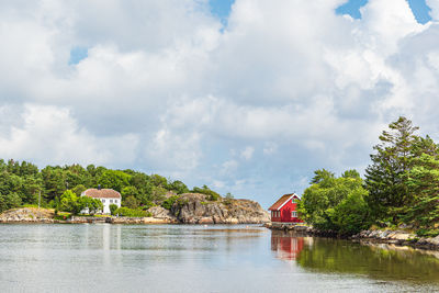 Buildings by river against sky