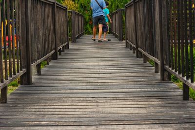 Rear view of man walking on footbridge