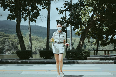 Confident young women hand holding ice beverage walking crossing street